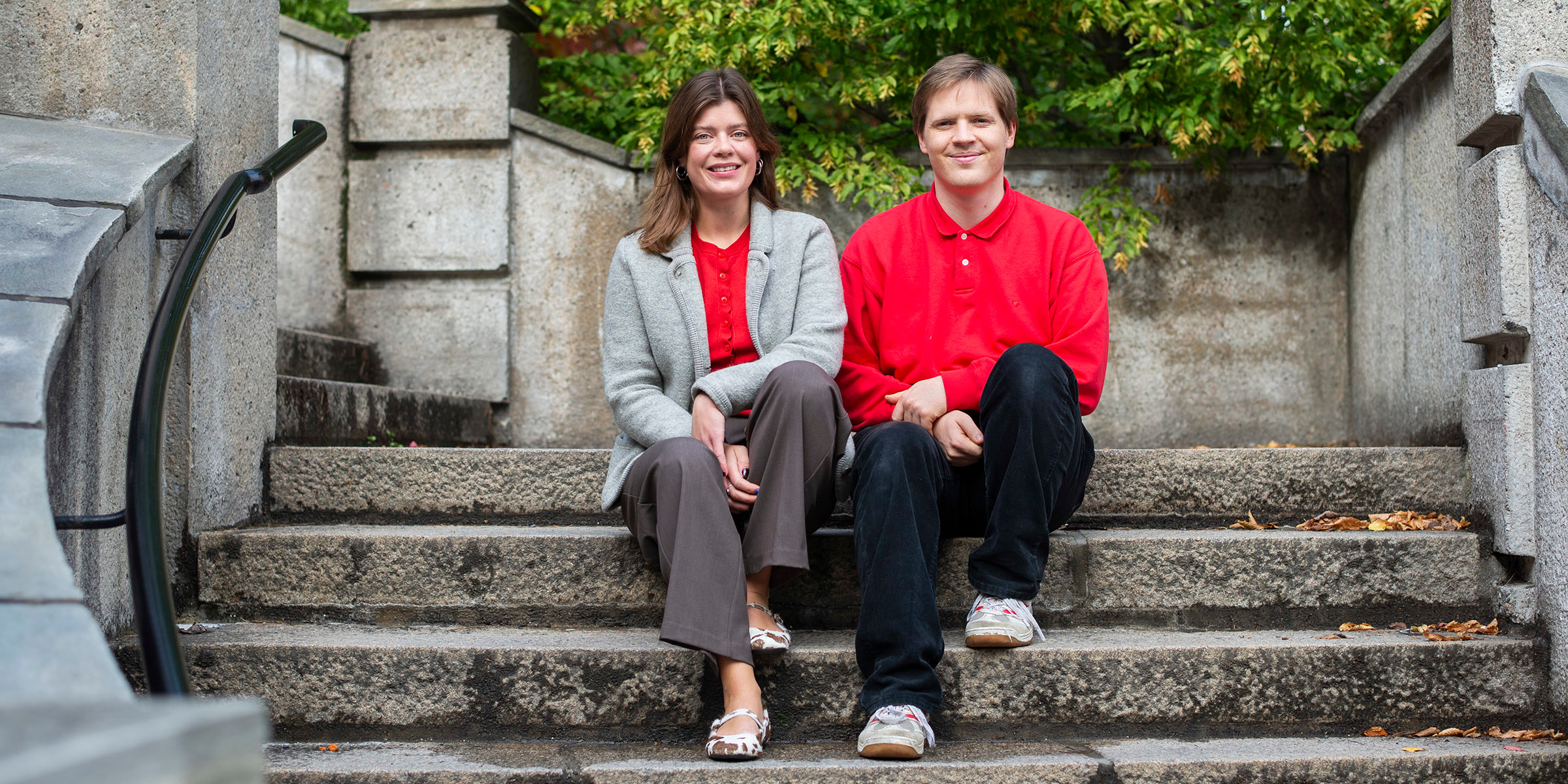 Portrait of the student ombuds Rebekka and Martin sitting outdoors on a stone staircase.