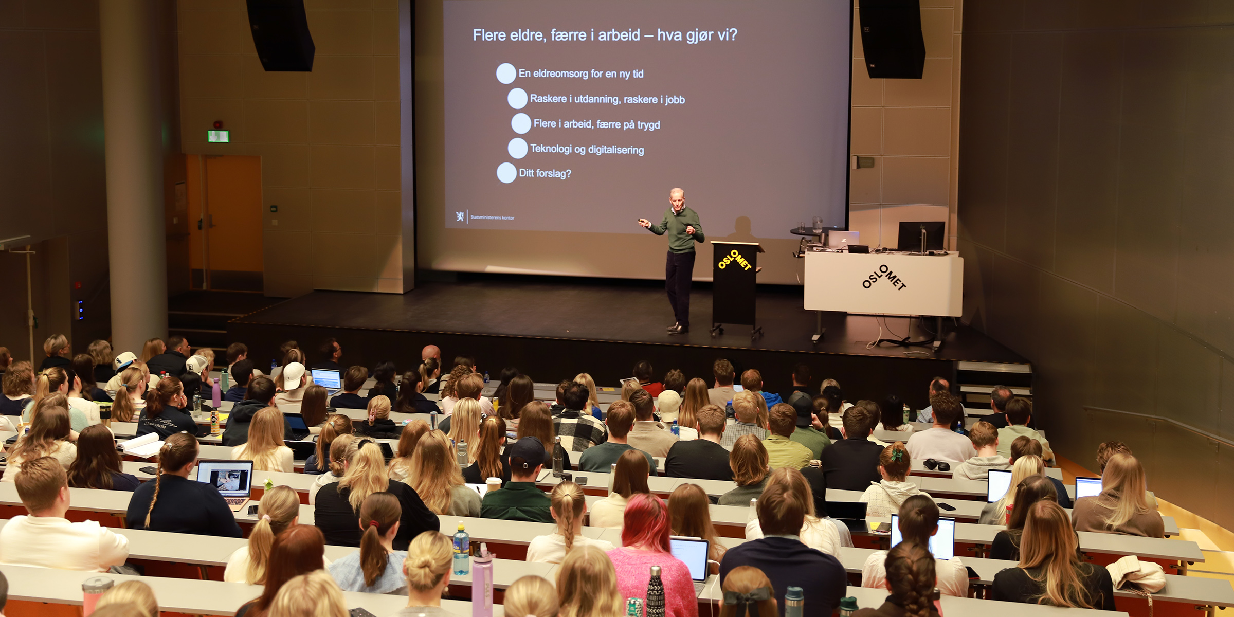 Jonas Gahr Støre på scenen i et fullsatt auditorium.