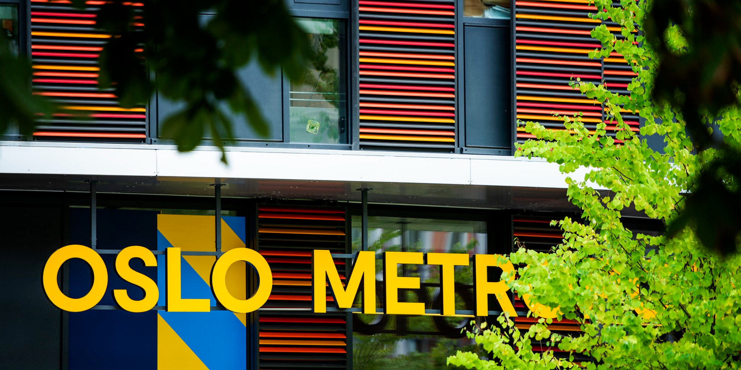 OsloMet-logoen i gul skrift på fasaden av et bygg.