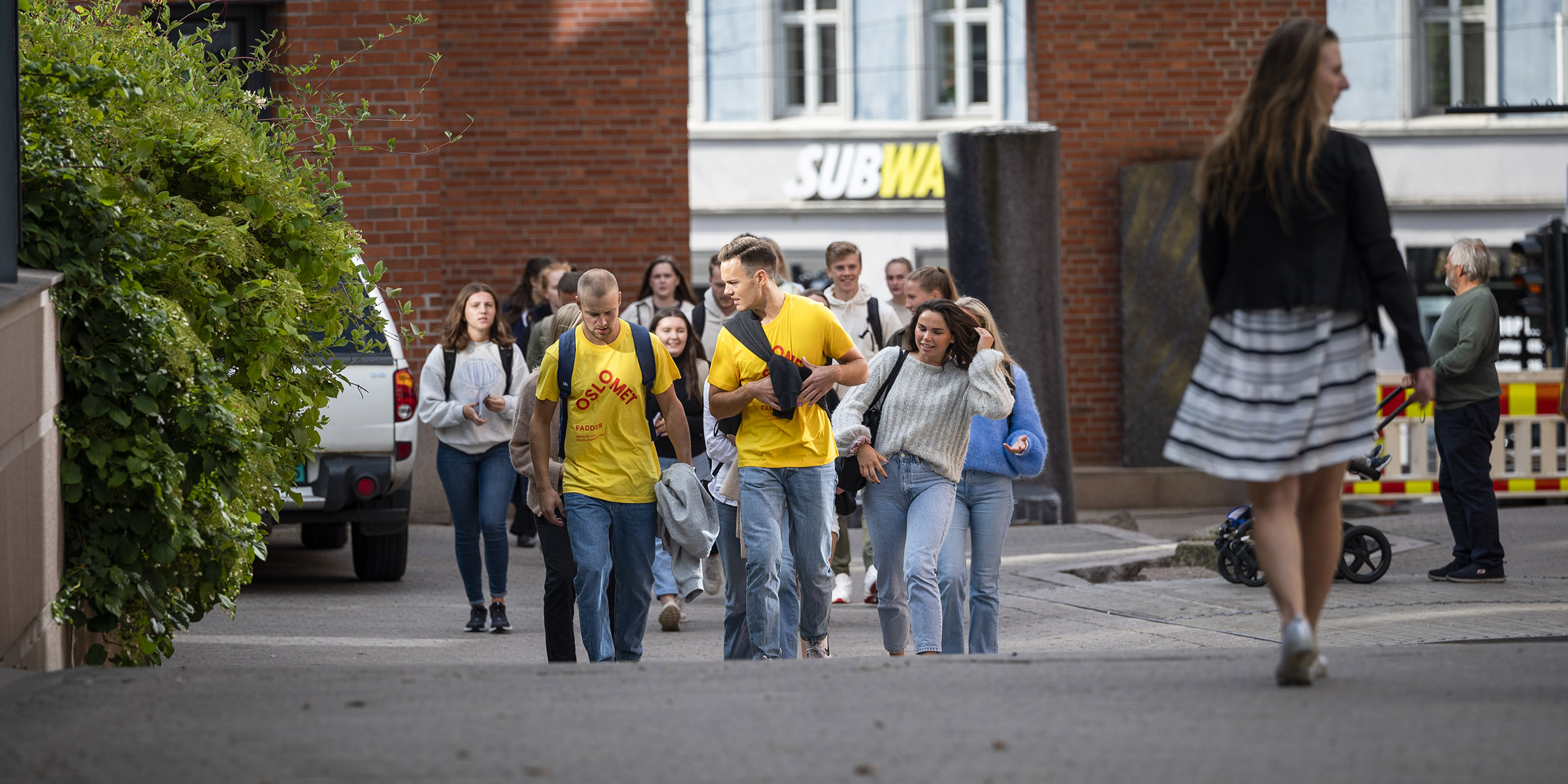 Nye studenter som følger etter faddere med gule t-skjorter ute på Campus Pilestredet.