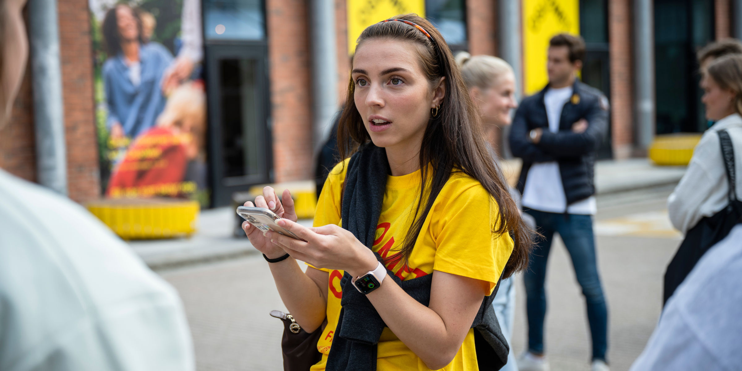 OsloMet-student står ute på campus og ser opp fra mobiltelefonen sin.