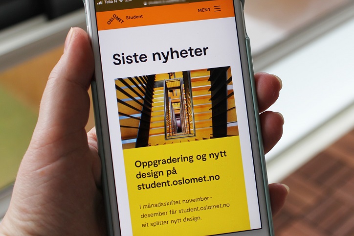 En hånd holder en mobiltelefon som viser nytt design på nettsider for studenter