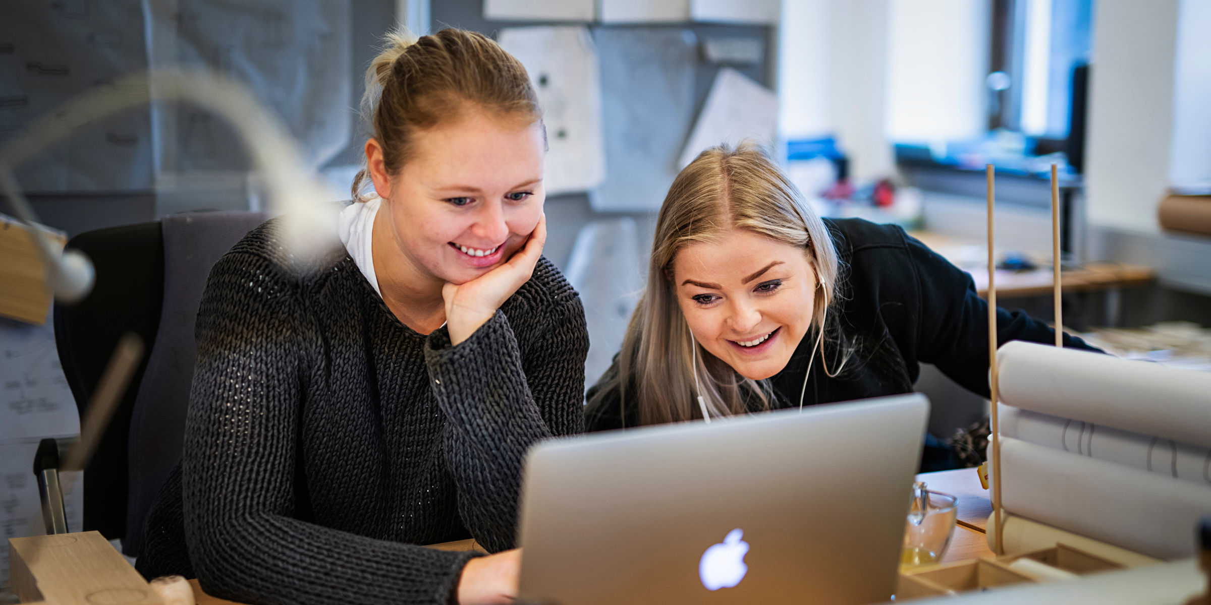 To studenter ser på en laptop. Begge smiler.