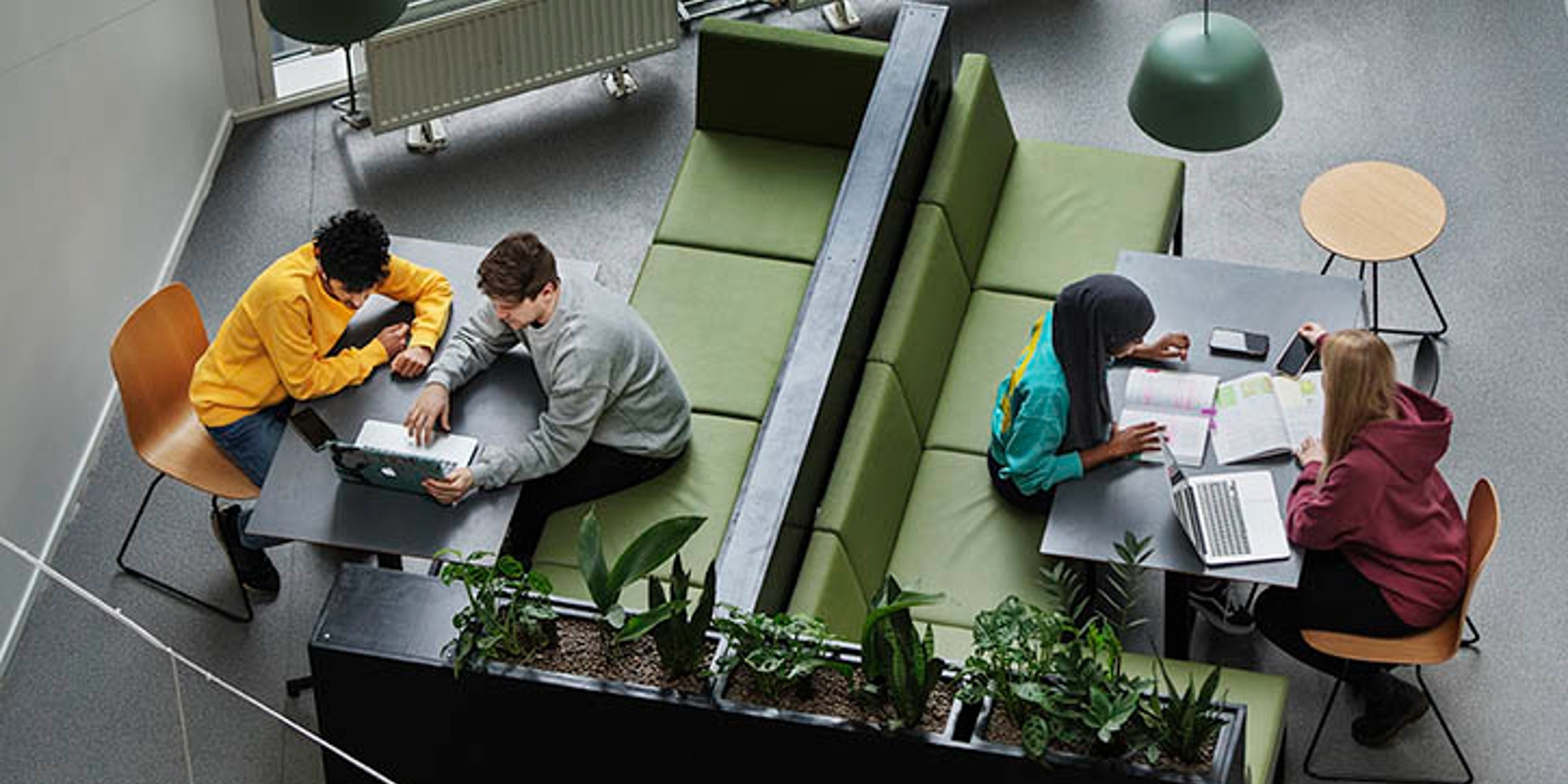4 studenter sett ovenfra, sitter ved bord med PC og papirer.