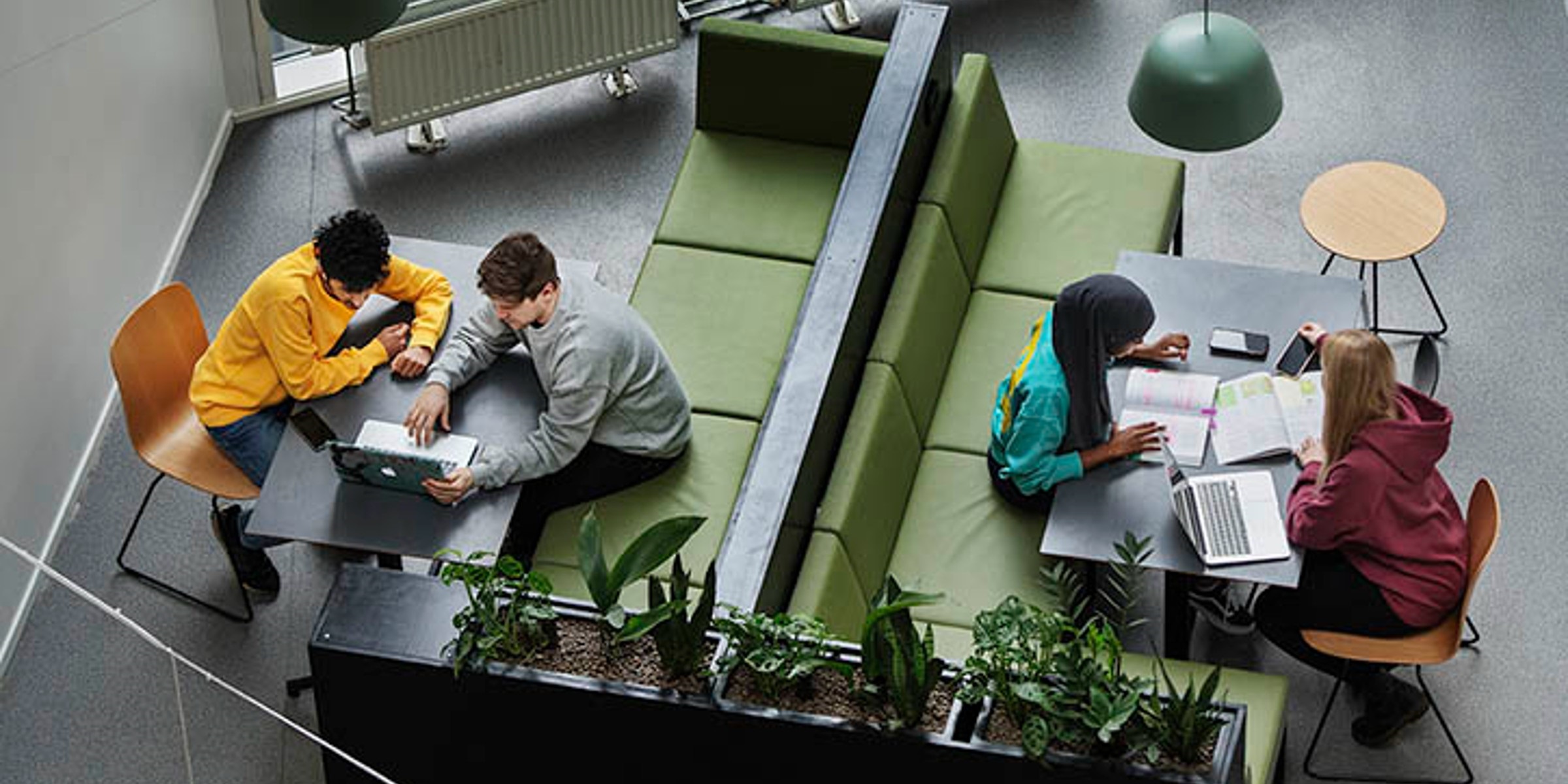 4 students seen from above, sitting by a table with PC and papers.