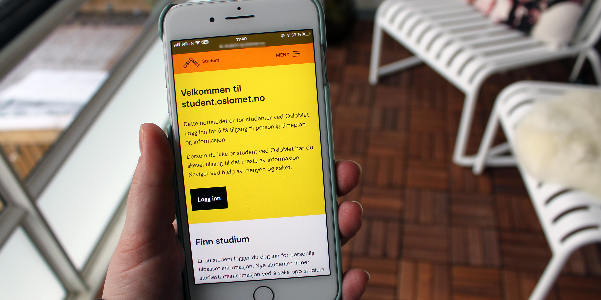Bilde av hand som held ein iPhone som viser det nye designet på student.oslomet.no.