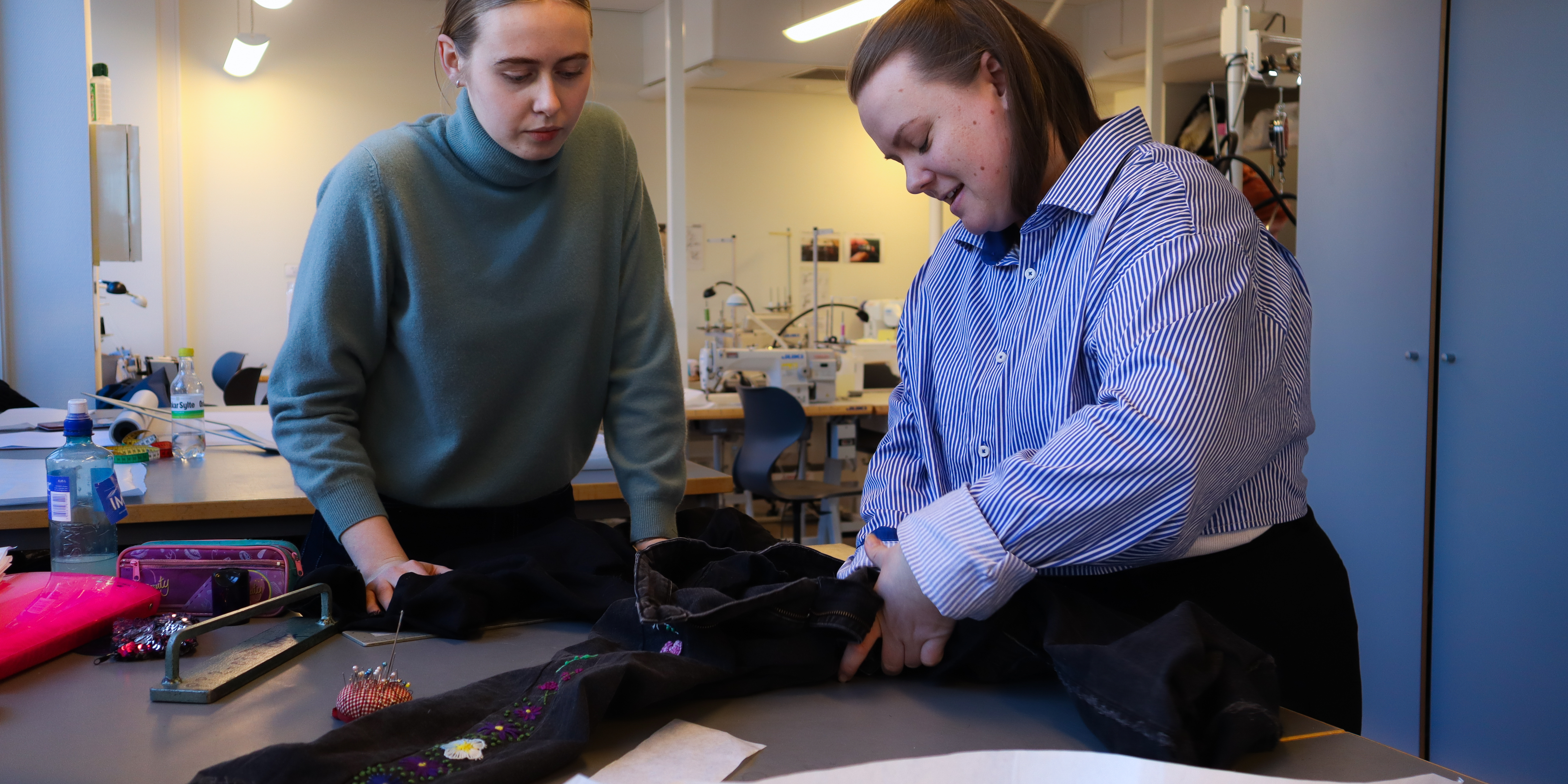 Art and design students Emilie and Anne repair a pair of trousers in a classroom at OsloMet.