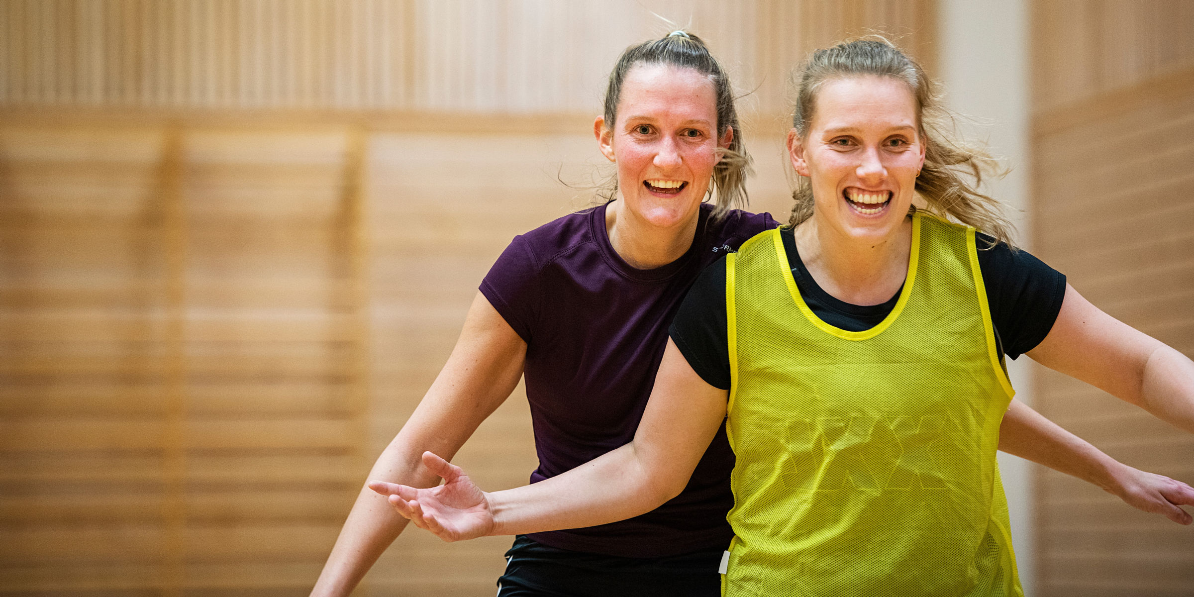 To blide OsloMet-studenter spiller håndball i en gymsal.