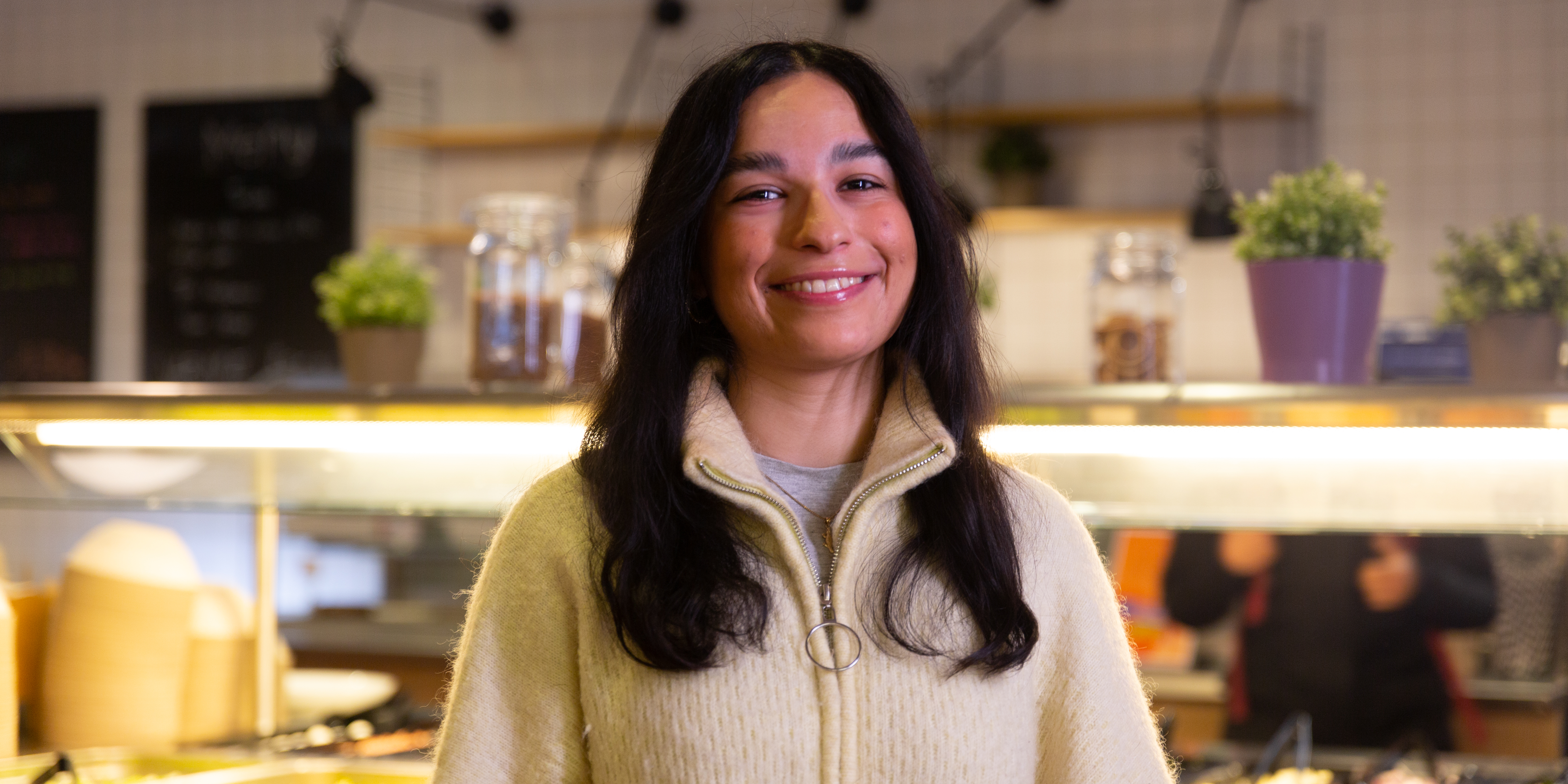 OsloMet-student Eileen Golamini smiler til kamera i universitetskantinen.