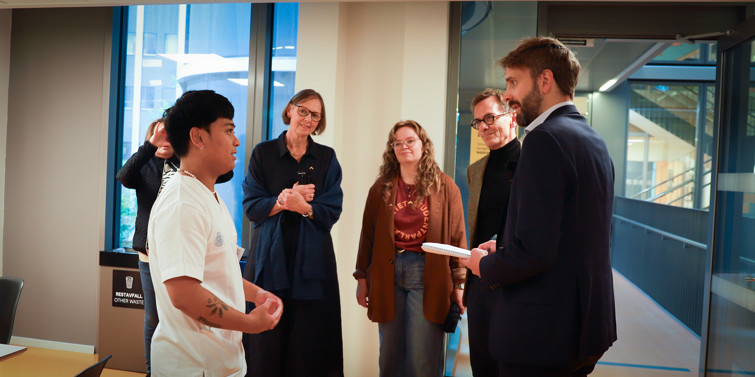 Student Ranndell Ryes Castillo i sykepleieruniform sammen med helseministeren, rektor, leder i Studentparlamentet og andre representater fra OsloMet.