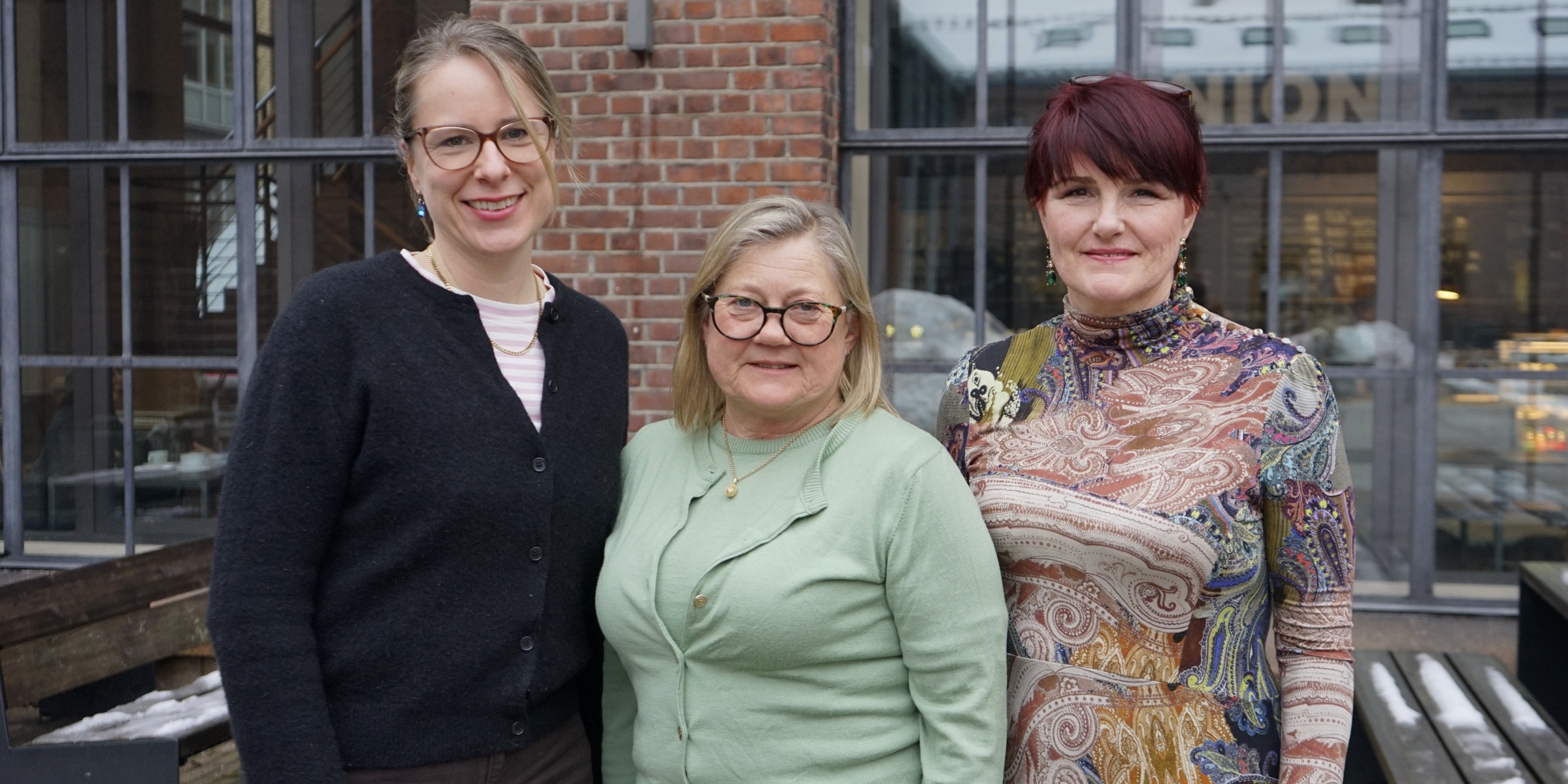 Kaja Granum Skarpaas, Ellen Merethe Magnus og Victoria Telle Hjellset står ved siden av hverandre med et bygg med store vinduer bak seg.